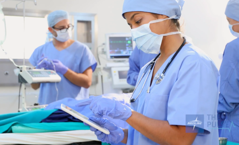 nurse inside an OR holding a tablet
