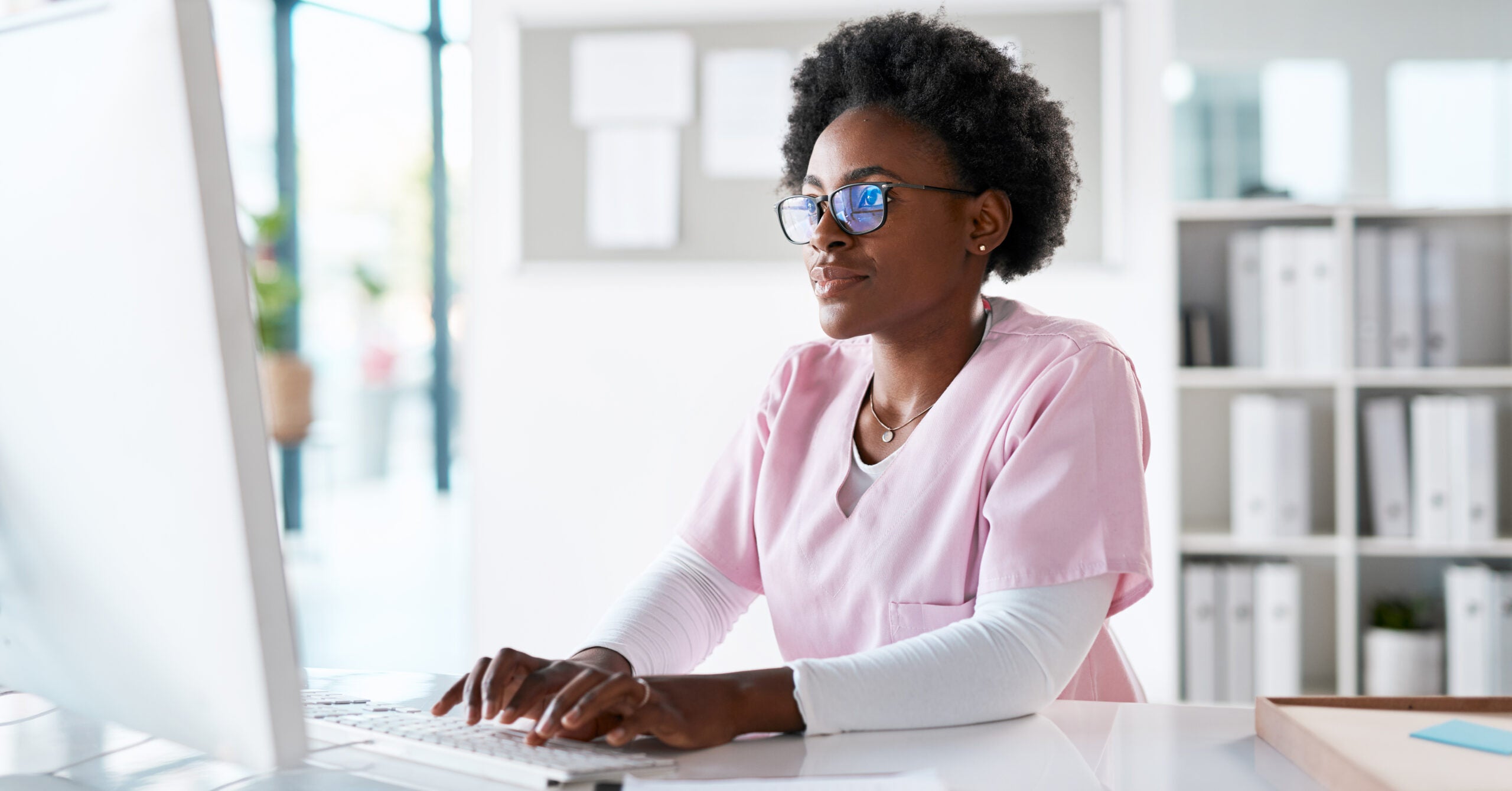 Nurse, medical and healthcare professional typing on computer in an office working online, internet and web. Black woman, worker and medicine expert doing administrative research work for a hospital