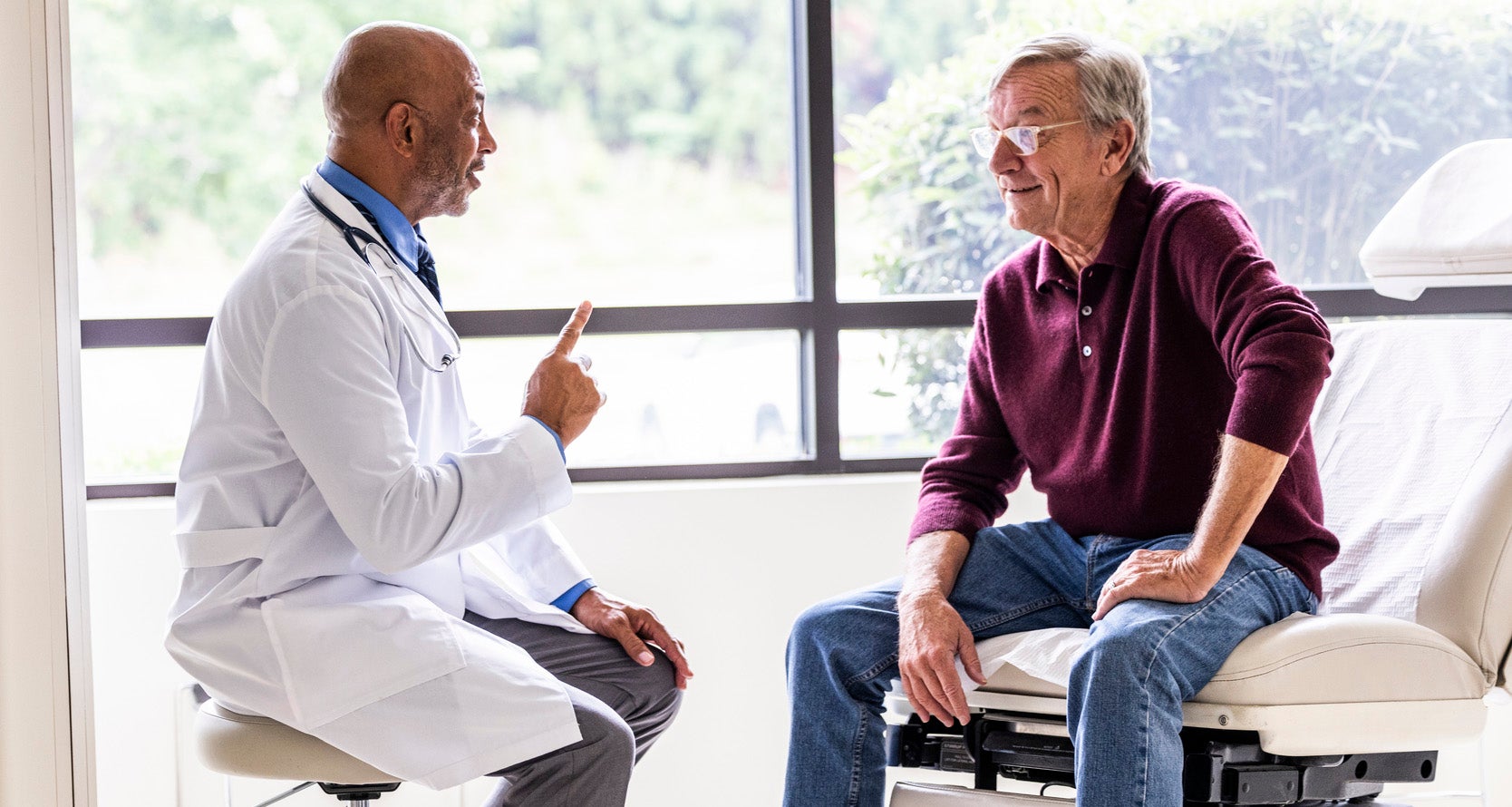 Male doctor talking with senior man in exam room